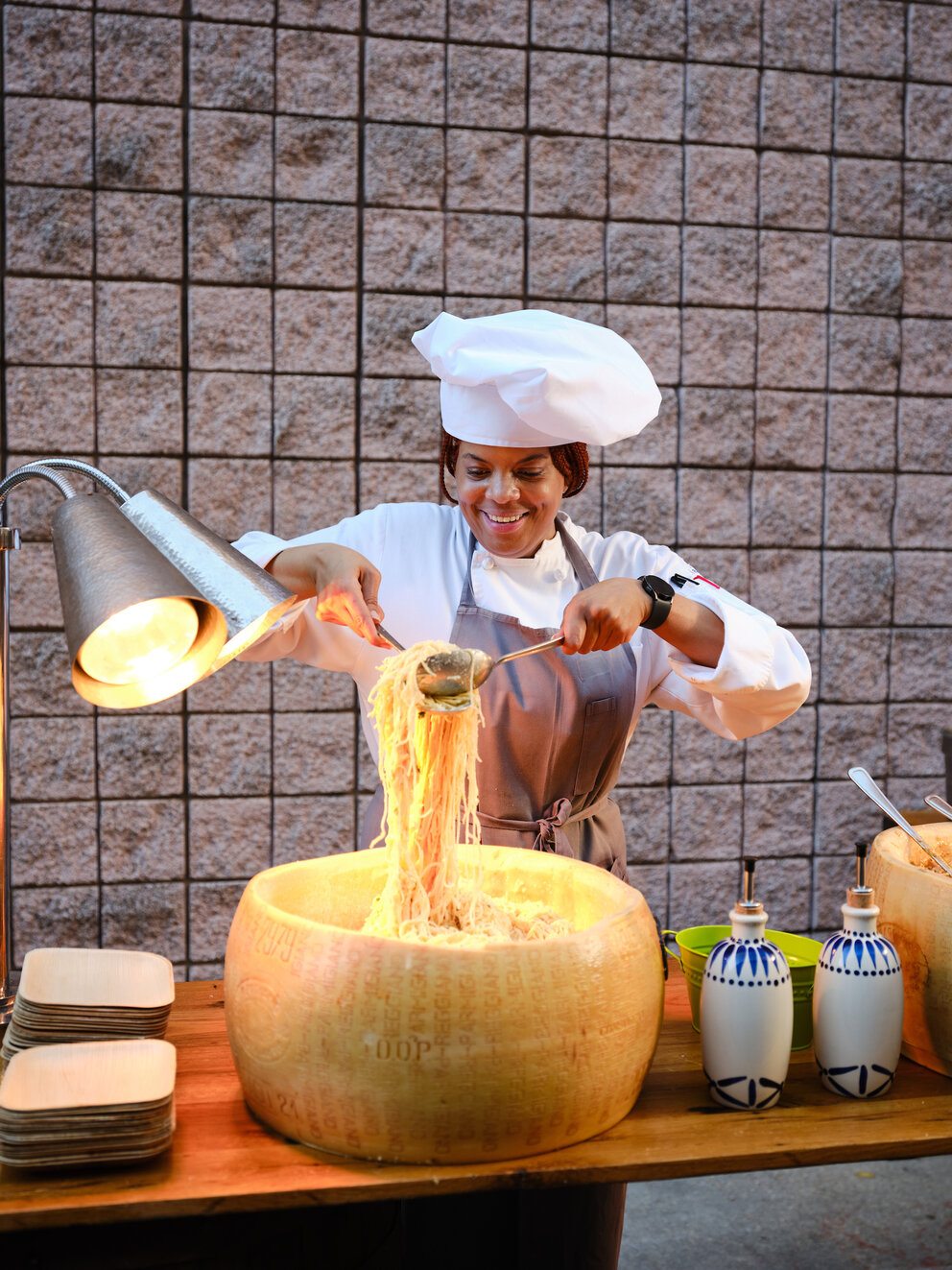 A woman tossing pasta in a parmesan wheel